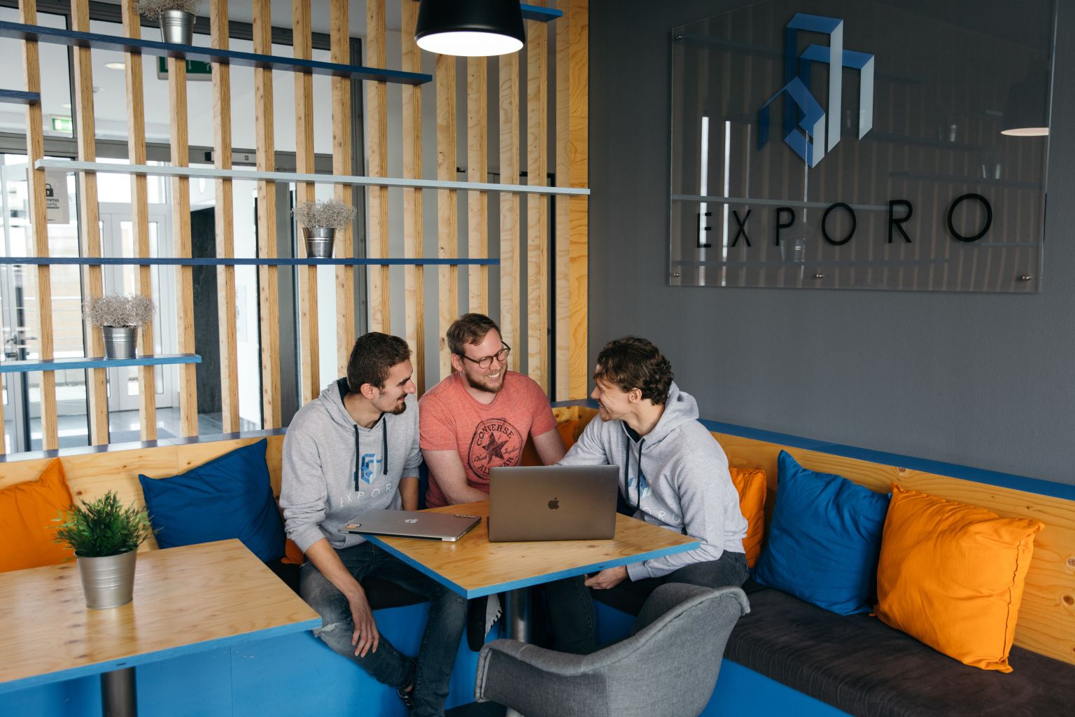 Трое мужчин сидят за ноутбуком в офисе компании Exporo.