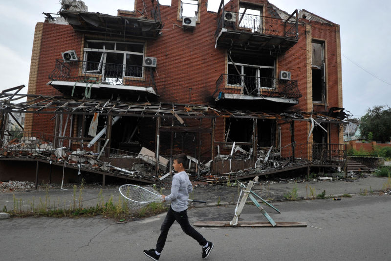 A boy walks past destroyed buildings in Ukraine