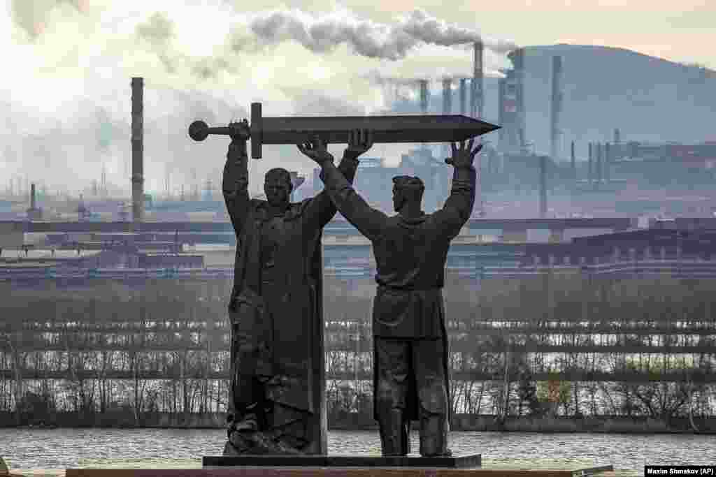 The Rear-Front Memorial in the Russian city of Magnitogorsk. The monument depicts a soldier and a steelworker holding a sword, with the worker facing the vast steel mills that supplied Soviet forces during World War II.