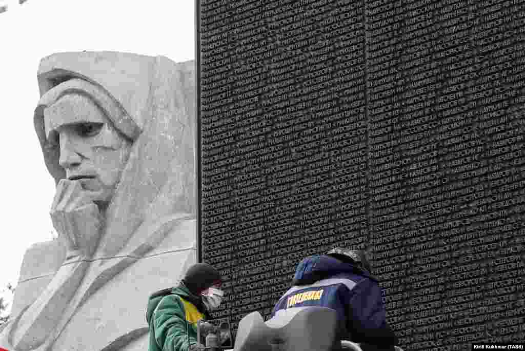 Workers clean the names of World War II soldiers at the Glory Monument in Novosibirsk on April 13, 2020.  