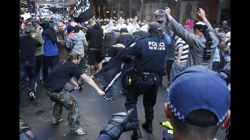 A protester hits a policeman with a pole in Sydney's central business district on Saturday, September 15. Anger over an anti-Islam video, 