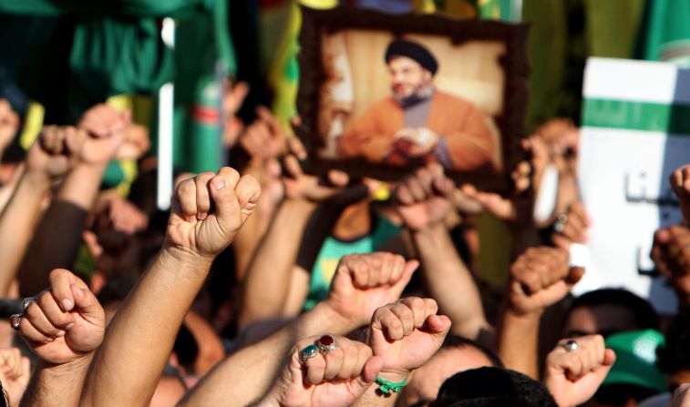 Supporters of Hezbollah hold a picture depicting Hezbollah leader Hassan Nasrallah and chant the slogan 