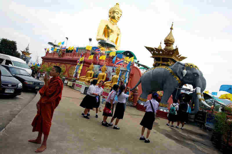 Schoolgirls take photographs of the elephant statue near the giant golden Buddha at Sop Ruak.