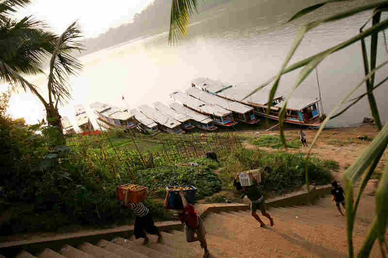 Workers unload produce from boats at a dock on the Mekong in Luang Prabang, Laos.