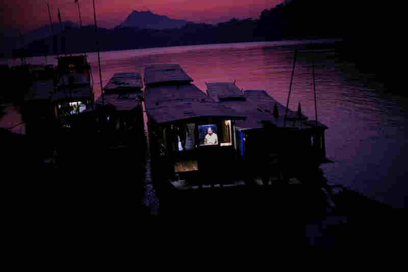 At sunset, a woman works on her boat on the Mekong in Luang Prabang.