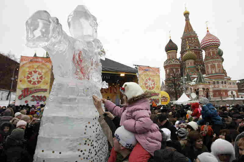 People stick coins to an ice sculpture of Lady Maslenitsa in front of St. Basil's Cathedral just outside the Kremlin on Feb. 14, 2010, during the last day of Maslenitsa celebrations.