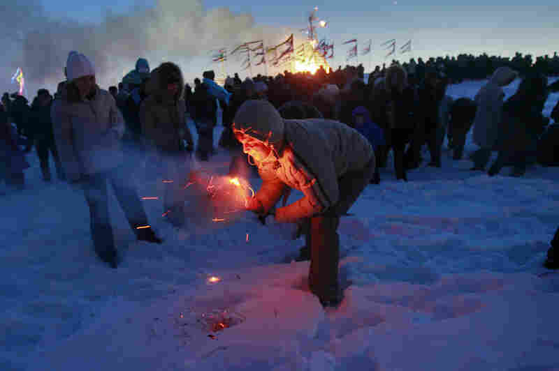 A man tries to burn a small effigy of Lady Maslenitsa during the final evening of festivities in 2011 in St. Petersburg, Russia. The torching marks the end of the holiday — a fiery goodbye to "lady winter." A larger straw effigy burns in the distance.