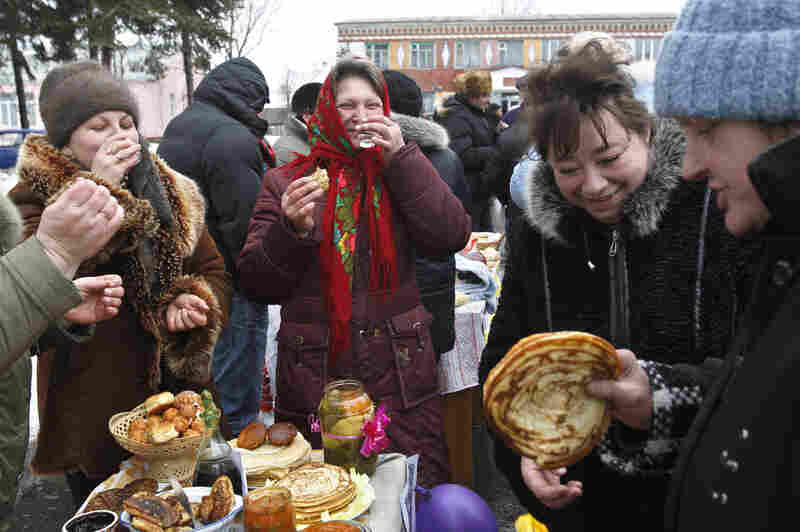 Belarusian woman drink vodka and sample more traditionally sized blinis.