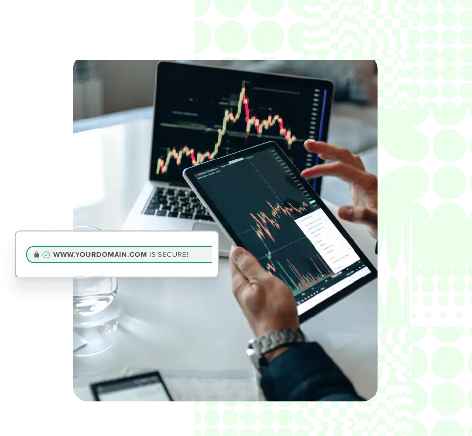 A pair of hands holding a tablet with a laptop computer in the background and both have a blurry screenshot of a random line graph.