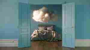 A cloud image over a bed, representing dreaming.