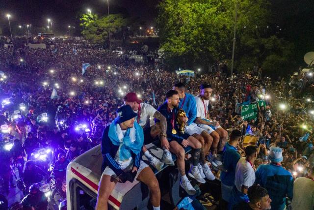 Argentina's captain and forward Lionel Messi (C) holds the FIFA World Cup Trophy on board a bus as he celebrates alongside teammates and supporters after winning the Qatar 2022 World Cup tournament (AFP via Getty Images)